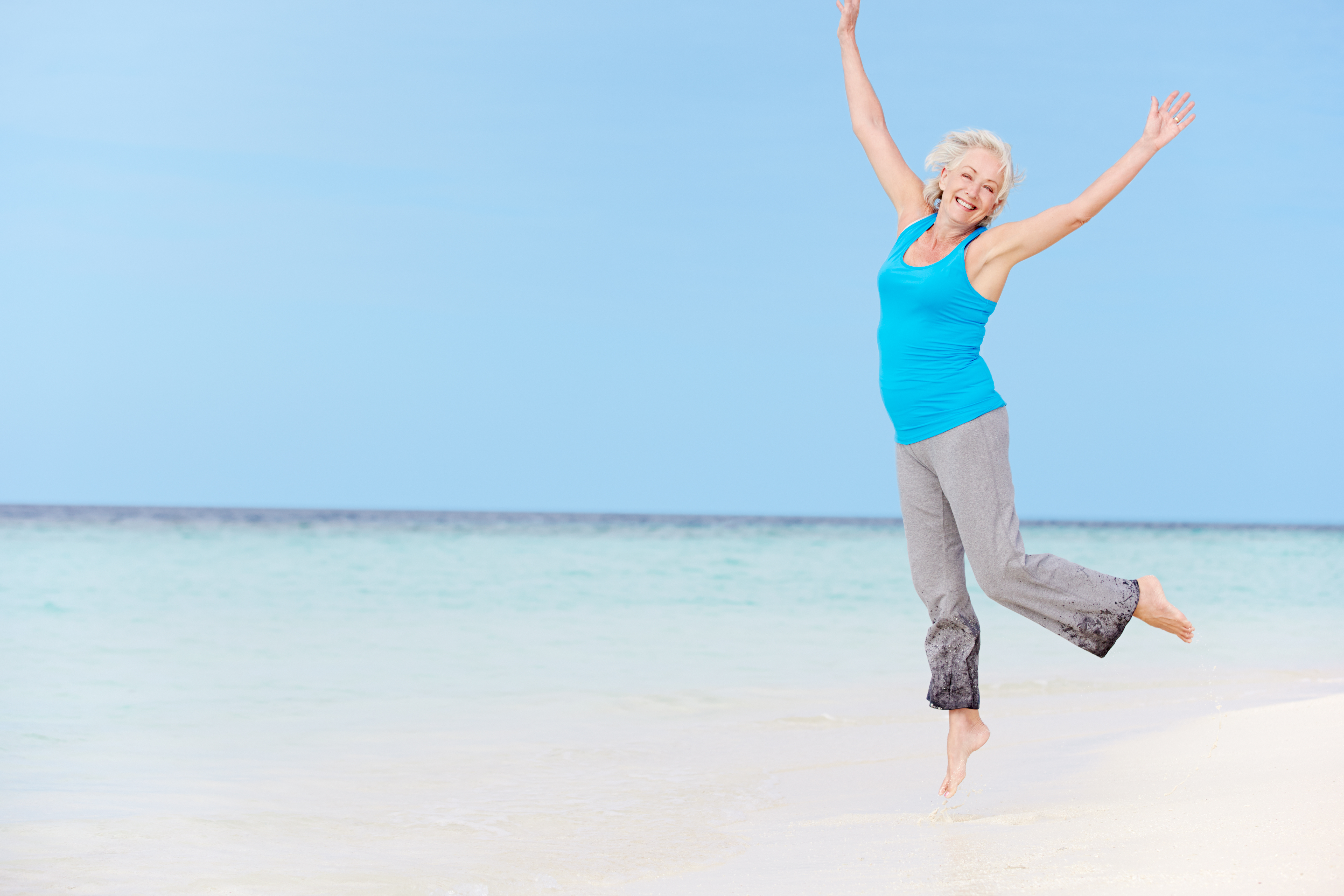 Senior Woman Jumping On Beautiful Beach
